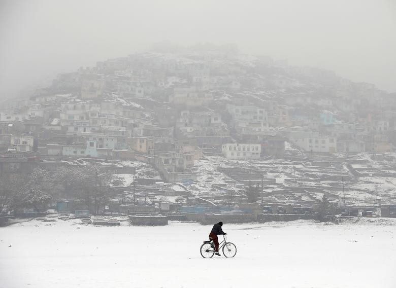 An Afghan man rides a bicycle during snowfall in Kabul, Afghanistan November 23. REUTERS/Mohammad Ismail